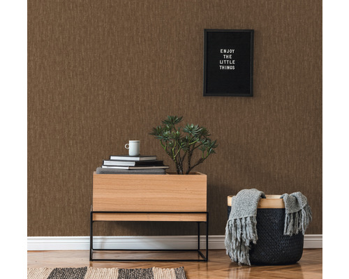 Dekoratives Interieur mit brauner Vinyltapete, Holztisch, Pflanze, Büchern und Korb