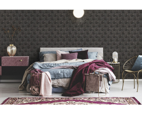 Schlafzimmer mit Bett, Nachttisch, Sessel und geometrischer Tapete