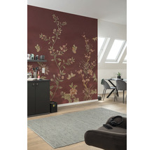 Wohnzimmer mit floral gemusterter Tapete in Rotbraun, Esstisch, Stühlen und grauem Teppich.