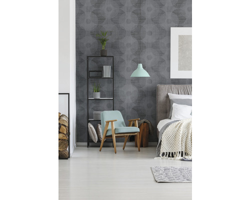 Schlafzimmer mit Bett, Sessel, Regal und grauer Mustertapete