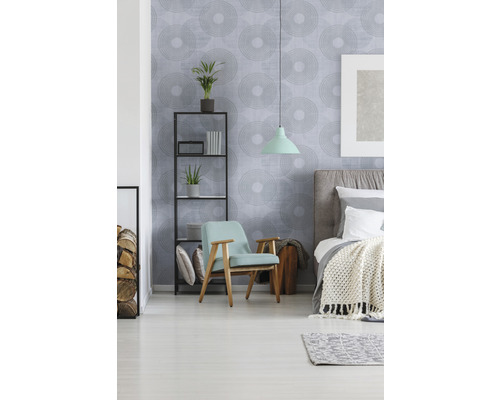 Helles Schlafzimmer mit Bett, Sessel, Regal und gemusterter Tapete