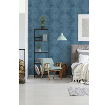 Schlafzimmer mit blau gemusterter Tapete, Bett, Sessel und Regal