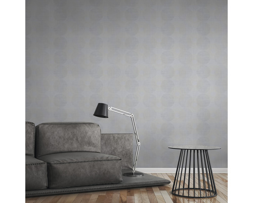 Ein Wohnzimmer mit Sofa, Stehlampe und Beistelltisch vor einer Wand mit Mustertapete