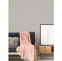 Wohnszene mit Tapete, Sofa, Kissen, Decke, Bild und Kommode