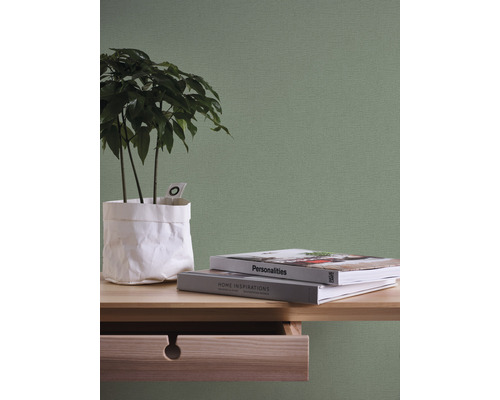 Nahaufnahme eines Arbeitsbereichs mit Pflanze, Büchern und einer Wandtapete