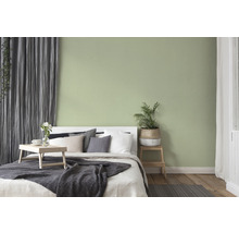 Schlafzimmer mit Bett, Nachttisch und dezent grün gestrichener Wand