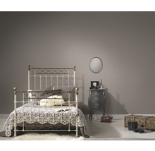 Schlafzimmer mit Bettgestell aus Metall, Nachttisch und runden Spiegel an der Wand