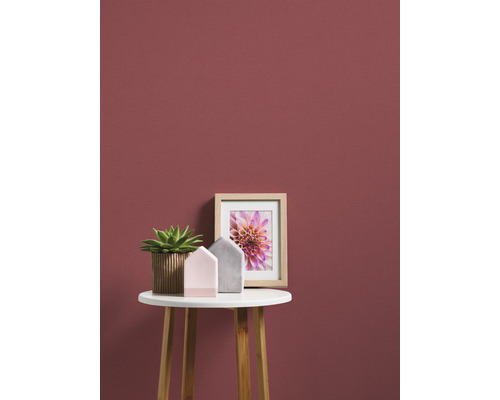 Dekoratives Stillleben mit Pflanze, Hausdekorationen und Bilderrahmen auf einem Tisch vor einer Wand