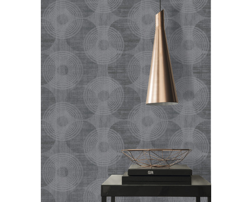 Nahaufnahme einer Wand mit geometrischer Tapete, einer Lampe und dekorativen Gegenständen auf einem Tisch