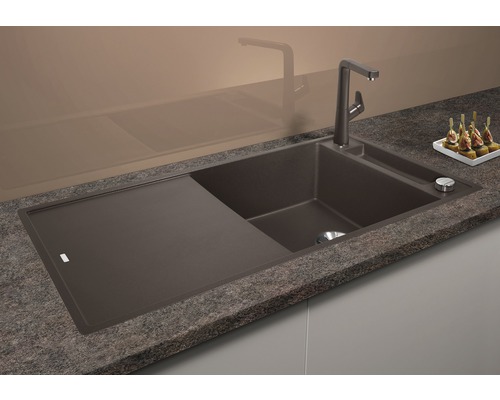 Spüle aus Verbundwerkstoff mit Abtropffläche und Armatur auf einer Küchentheke.