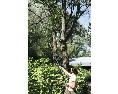 Frau benutzt eine Teleskop-Astschere im Garten, um Äste zu schneiden.
