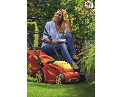 Wolf Garten Rasenmäher vor einer entspannten Frau im Garten