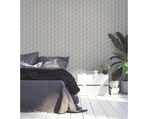 Schlafzimmer mit Bett, Nachttisch, Zimmerpflanzen und einer Wand mit dreidimensionaler geometrischer Tapete.