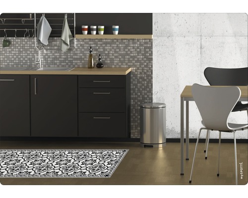 Küchenszene mit Spüle, Mülleimer, Stühlen und gemusterter Küchenmatte