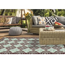 Szene mit Outdoor Teppich, Gartenmöbeln und Dekorationen auf einer Terrasse.