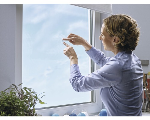 Frau bringt Sichtschutzfolie am Fenster an
