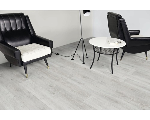 Wohnraum mit hellem Vinylboden, Sessel, Stehlampe und Beistelltisch