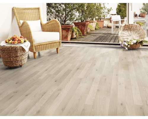 Heller Holzboden mit Korbsessel, Früchten und Blumen auf der Terrasse