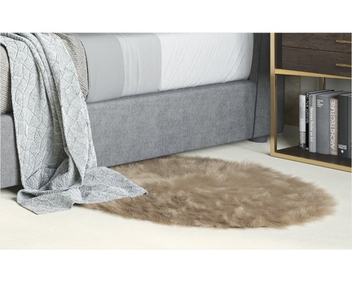 Dekoratives Schlafzimmerambiente mit Bett, Beistelltisch und einem ovalen Teppich