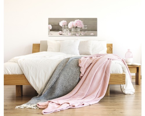 Schlafzimmer mit Bett, Decken und einem Bild von Blumen