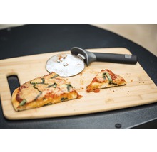 Zwei Pizzastücke und Pizzaschneider auf Holzschneidebrett