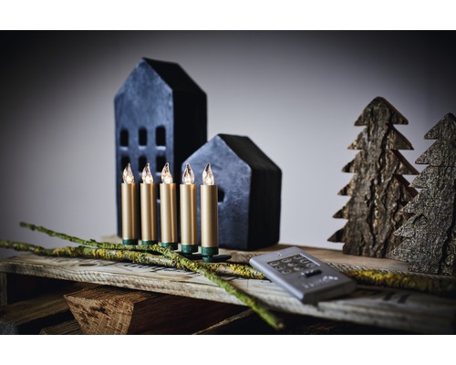 Dekorative LED-Lichterkette mit fünf Kerzen, Häusern und Bäumen auf einem Holztisch.