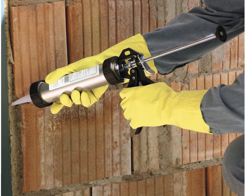 Handwerker verwendet eine Kartuschenpistole an einer Ziegelwand