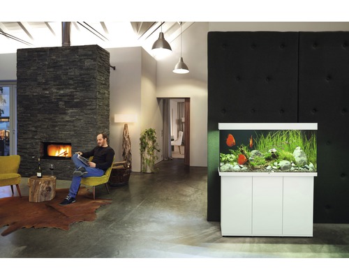 Wohnzimmer mit Aquarium und sitzendem Mann am Kamin.