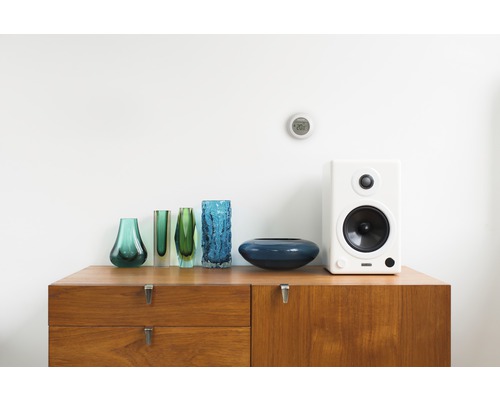 Wohnszene mit Holzkommode, Glasvasen, Lautsprecher und Thermostat