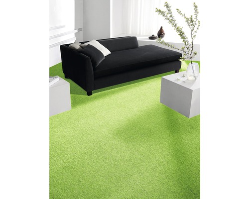 Wohnzimmer mit grasgrünem Teppichboden, schwarzem Sofa und weißen Beistelltischen.