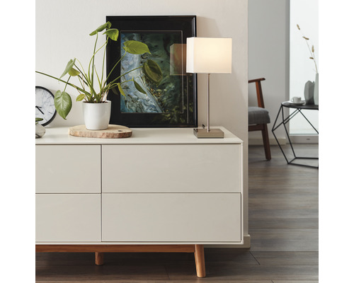 Kommode mit Dekoration, Tischleuchte und Bild im Rahmen in einem hellen Raum