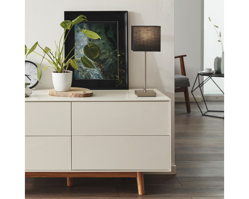 Modernes Interieur mit Kommode, Tischleuchte, Zimmerpflanze und Wandbild