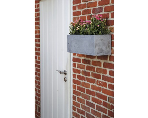 Blumenkasten aus Beton an einer Ziegelmauer neben einer Tür