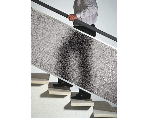 Mann trägt Dämmplatte die Treppe hoch.