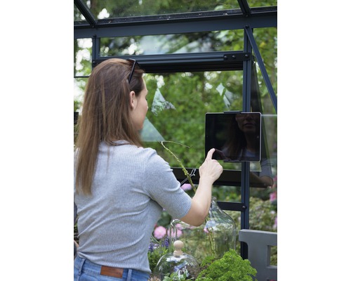 Frau bedient ein Tablet in einem Gewächshaus mit Pflanzen