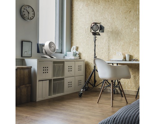 Ein Arbeitszimmer mit einem Schreibtisch, einem Regal und einem Ventilator