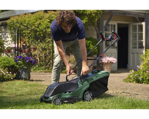 Ein Mann benutzt einen Bosch Rasenmäher im Garten.