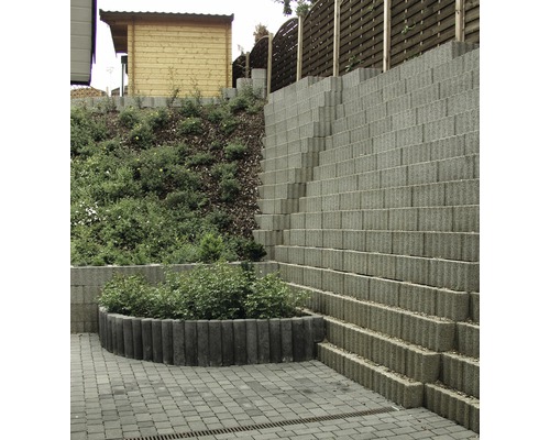 Gestufte Gartenmauer aus Betonsteinen mit Bepflanzung