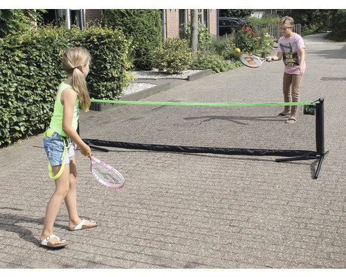 Zwei Kinder spielen mit einem tragbaren Tennisnetz im Freien.