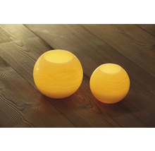 Zwei runde Windlichter aus Glas auf einem Holzboden
