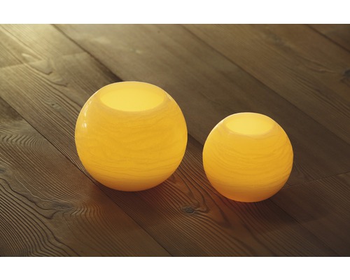 Zwei runde Windlichter aus Glas auf einem Holzboden
