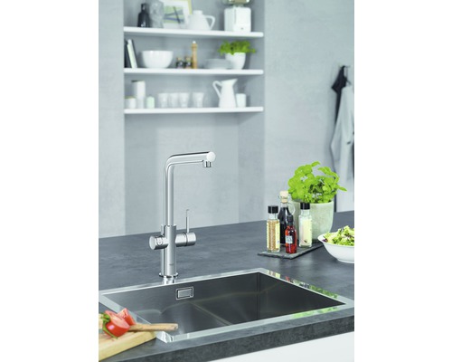 Moderne Küchenszene mit Spüle, Armatur und Küchenutensilien auf einer Arbeitsplatte.