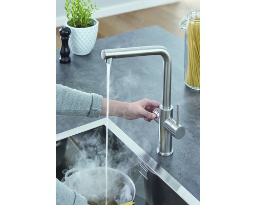 Küchenszene mit Armatur, Wasserhahn und kochendem Wasser im Spülbecken.