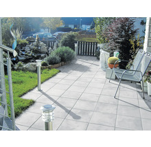 Terrasse mit Garten, ausgestattet mit Gartenmöbeln, Bodenplatten und Außenleuchten.