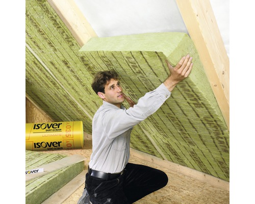Mann bringt Dämmwolle auf einem Dachboden an. Isover Logo.