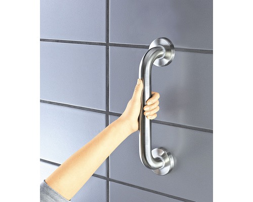 Eine Hand hält einen Haltegriff an einer gefliesten Wand für mehr Sicherheit im Badezimmer.