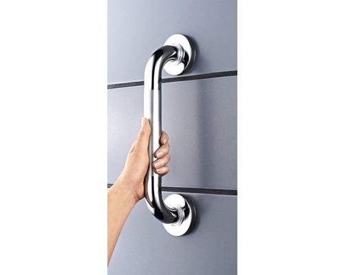 Eine Hand hält einen Haltegriff aus Metall an einer Wand.