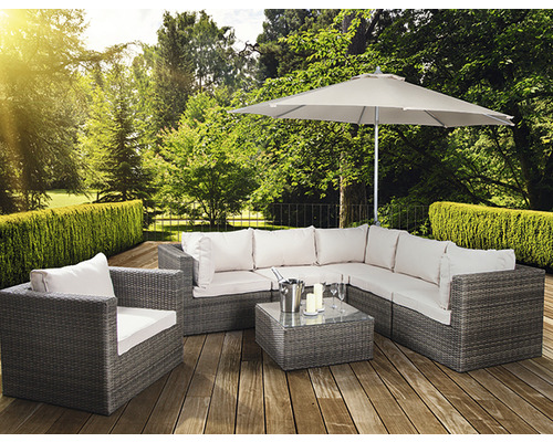 Gartenszene mit grauer Loungegruppe, Sessel, Tisch, Sonnenschirm und Dekoration auf einer Holzterrasse