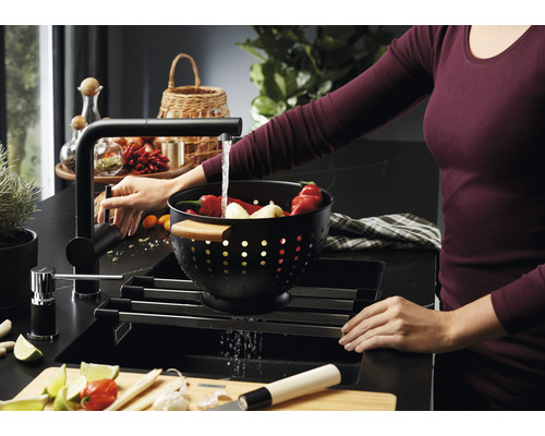 Spüle mit Abtropfgestell, Armatur und Frau beim Gemüsewaschen