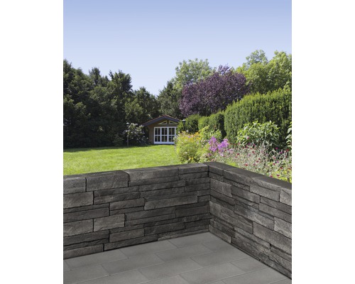 Garten mit Mauer aus Steinpaneelen und Gartenhaus